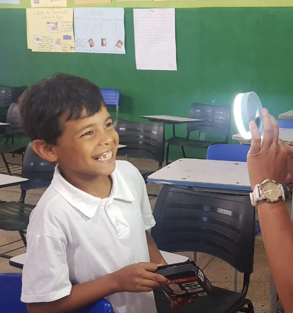 A foto mostra uma criança sorrindo enquanto está sendo filmada em uma das últimas formações do projeto