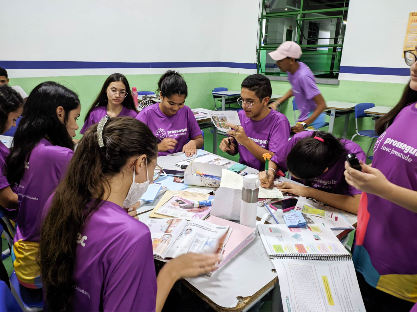 Jovens comunicadores reunidos na mesa fazendo colagens para zines